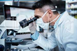 Working on a new clinical trial. a mature man using a microscope while conducting pharmaceutical research.