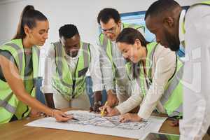 Closeup of a happy diverse multiracial group of architect colleagues analyzing a blueprint design on a building and discussing plans for the next project. Team of young and senior designers working on a strategy for a building construction plan while wear