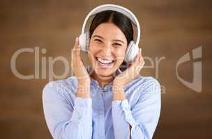 Happy young mixed race businesswoman wearing wireless headphones at work. One female only enjoying listening to relaxing music and songs, audio books or podcast for stress relief while on a break