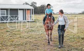 Horse riding has always been something I wanted to do. a female instructor taking a little girl horse riding.