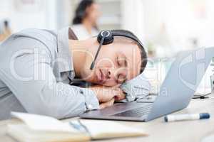 Its been a quiet day. a young call centre agent sleeping at his desk in an office.