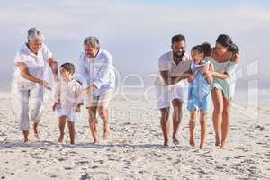 Playful multi generation family on vacation having fun at the beach. Mixed race family with two children, two parents and grandparents spending time together by the sea