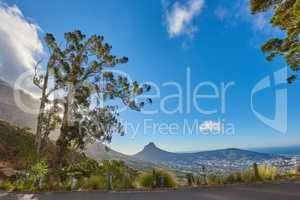 Road or street leading to a scenic mountain view with blue sky during a summer roadtrip in Cape Town, South Africa. Landscape of lush green hills and a mountain pass for weekend exploring and driving