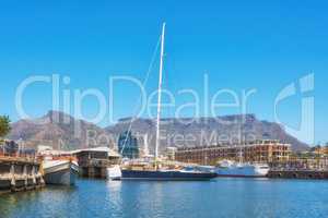 Sailboats docked at a harbor with Table Mountain in the background against blue sky with copy space. Scenic landscape of waterfront port at a marina dockyard. Nautical vessels for travel and tourism