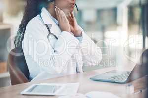 Closeup african american woman doctor using her laptop to do an online remote consult while sitting in her office in the hospital. Testing during the pandemic outbreak. Stop the spread of covid 19