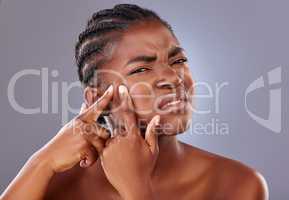 They just pop up and ruin my day. Shot of a young woman squeezing a pimple on her face.