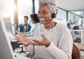 Happy african american call centre telemarketing agent talking on a headset while working on a computer in an office. Confident friendly female consultant operating a helpdesk for customer service and sales support