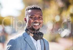 African American man wearing headphones while out in the city. Portrait of a happy handsome black male enjoying music on his daily commute to work. young businessman outside