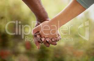 Closeup of biracial couple interlocking their fingers and holding hands while bonding in the garden at home. Mixed race woman united with African American man. Standing together in support and love