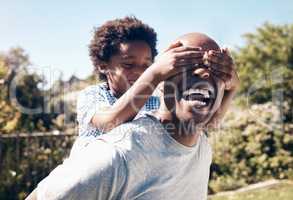 a happy african american man bonding with his young little boy outside. Two black male father and son looking happy and positive while being affectionate and playing in a backyard