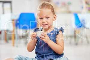 Portrat of one adorable little caucasian girl sitting alone in preschool and holding a small teacup. Smiling child playing and having a tea party at school. Social skills develop children at creche