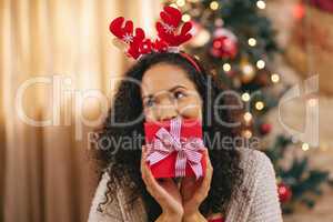 Guess what Santa got you this year. a happy young woman opening presents during Christmas at home.