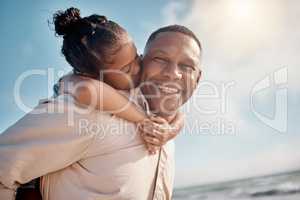 Smiling mixed race single father carrying little daughter on piggyback with copyspace. Adorable, happy, hispanic girl bonding with parent and kissing cheek on beach. Man and child enjoying free time