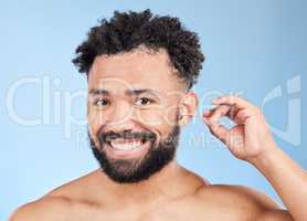 So I can hear you clearly. Studio portrait of a handsome young man cleaning his ears against a blue background.