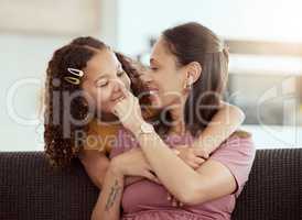 Mixed race single mother and daughter hugging in home living room. Smiling hispanic girl embracing and bonding with single parent in lounge. Happy affectionate woman and child together on weekend