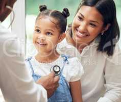 Doctor examining happy little girl by stethoscope. Child sitting with mother while male paediatrician listen to chest heartbeat. Mom holding daughter during doctor visit