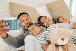 Everyone, say cheese. a beautiful young family talking and bonding in bed together.