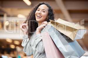 Portrait beautiful mixed race woman standing in a mall while out on a shopping spree. Young hispanic woman carrying bags, spending money, looking for sales and getting in some good retail therapy