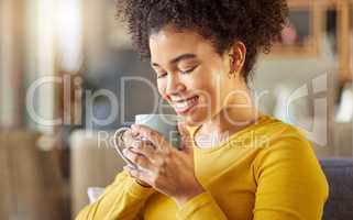 Young happy mixed race woman holding and drinking a cup of coffee at home. One cozy hispanic female smiling and enjoying a cup of tea while relaxing at home