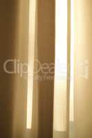 Closed linen curtains hanging on window on a sunny day inside a modern home. Shadow and sunlight shining through cream cotton or beige fabric for interior decoration and copy space background