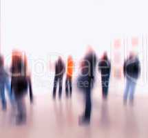 Blurred people browsing and looking at display at an art exhibition or museum. Group of businesspeople networking at a trade fair. Big room or hall with obscured figures standing and looking around