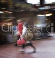 Blurred motion of a couple commuting through an urban town. Man and woman rushing while walking together in a street in the city. Tourists traveling and exploring abroad in defocused movement