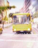 A yellow bus driving and traveling through a bust scene in the city. Commuting through a busy urban town, using public transport to travel the roads and streets to get to a destination