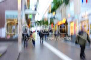 Blurred motion of people traveling in a city outside. Defocused on crowd population of tourists, travelers and pedestrians exploring abroad while walking in a bustling and busy urban street downtown