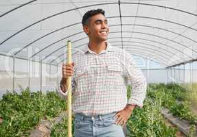 Getting his daily tasks done on time. a young man using a gardening tool while working in a greenhouse on a farm.