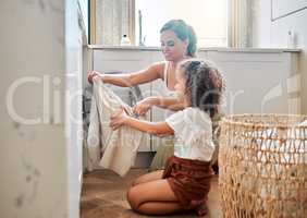 Young hispanic mother and her daughter sorting dirty laundry in the washing machine at home. Adorable little girl and her mother doing chores together at home