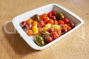 Food stuff. Closeup of roma or cherry tomatoes in a glass bowl served on a wooden table for diet, healthy salads and nutrition. Fresh, organic fruit farmed in home garden or agriculture farm.