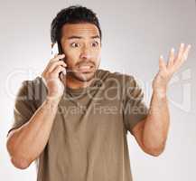 Handsome young mixed race man looking irritated, aggravated or agitated while using his phone in studio isolated against a grey background. Displeased hispanic male making a call to complain or argue