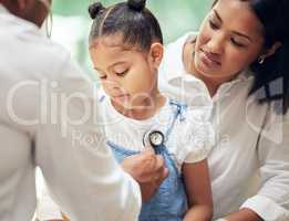 Doctor examining little girl by stethoscope. Sick girl sitting with mother while male paediatrician listen to chest heartbeat. Mom holding daughter during doctor visit