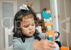 Really goos for hand and eye coordination. Shot of a cute little girl playing with building blocks at the kitchen table.