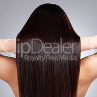 Look at that healthy shine. Rearview shot of a young woman with long silky hair posing against a grey background.