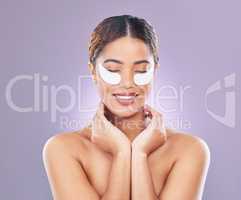 Puffy eyes for who. a young woman using eye masks against a pink background.