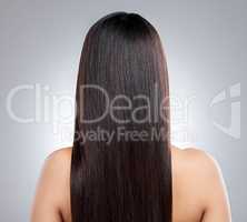 I love it all smooth and sleek. Rearview shot of a young woman with long silky hair posing against a grey background.