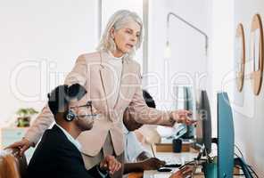 You learn by asking questions. a mature businesswoman standing and talking to a young agent while he uses his computer.