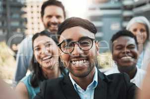 Say cheese. a handsome young businessman standing outside with his colleagues and taking selfies.