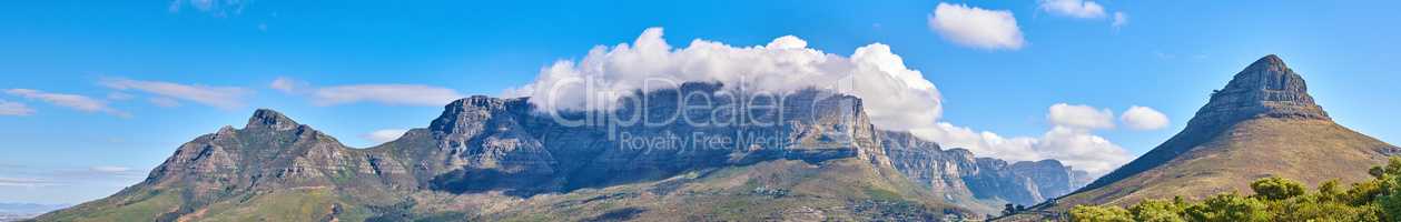Panoramic landscape of the majestic Table Mountain and Lions Head in Cape Town, Western Cape. A cloudscape sky with copy space over large mountainous and hilly terrain in peaceful nature