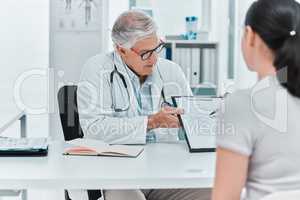 I need you to fill this out. a mature doctor sitting with his patient and showing a medical chart during a consultation in his clinic.