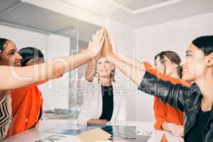 Supporting each other all the way to the top. a group of businesswoman giving each other a high five in an office at work.