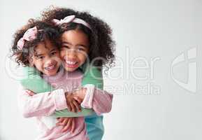 Our baby girls are so adorable from head to toe. two adorable little girls hugging and standing together against a grey background.