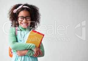 We asked for a daughter, we were sent a princess. a little girl wearing glasses and holding books against a grey background.
