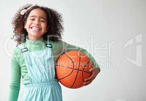 Such a big miracle in such a little girl. a little girl holding a basketball against a grey background.