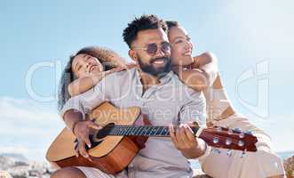 The bond between friends is a special one. a young man playing the guitar while at the beach with his friend.