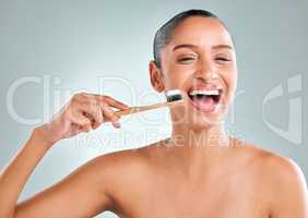 Good hygiene is like money in the health bank. Studio shot of an attractive young woman brushing her teeth against a grey background.