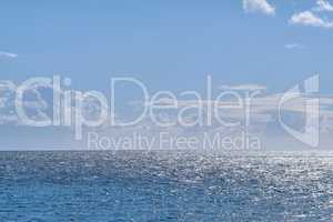 Beautiful puffy clouds in a blue sky rolling over a calm blue sea and ocean in summer. Gorgeous scenic view of the beach and blue water during the day at low tide. Idyllic and peaceful coastline