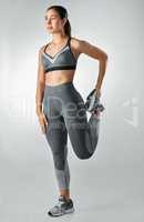 Because nobody has time for tense muscles. Studio shot of a sporty young woman stretching her legs against a grey background.