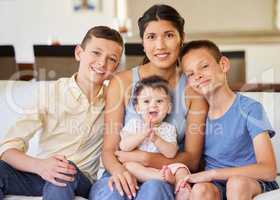 Portrait of a multiracial family at home.Mother with her adoptive sons. Young mother relaxing with her children. Mixed race family relaxing together at home. Boys spending time with their parent.